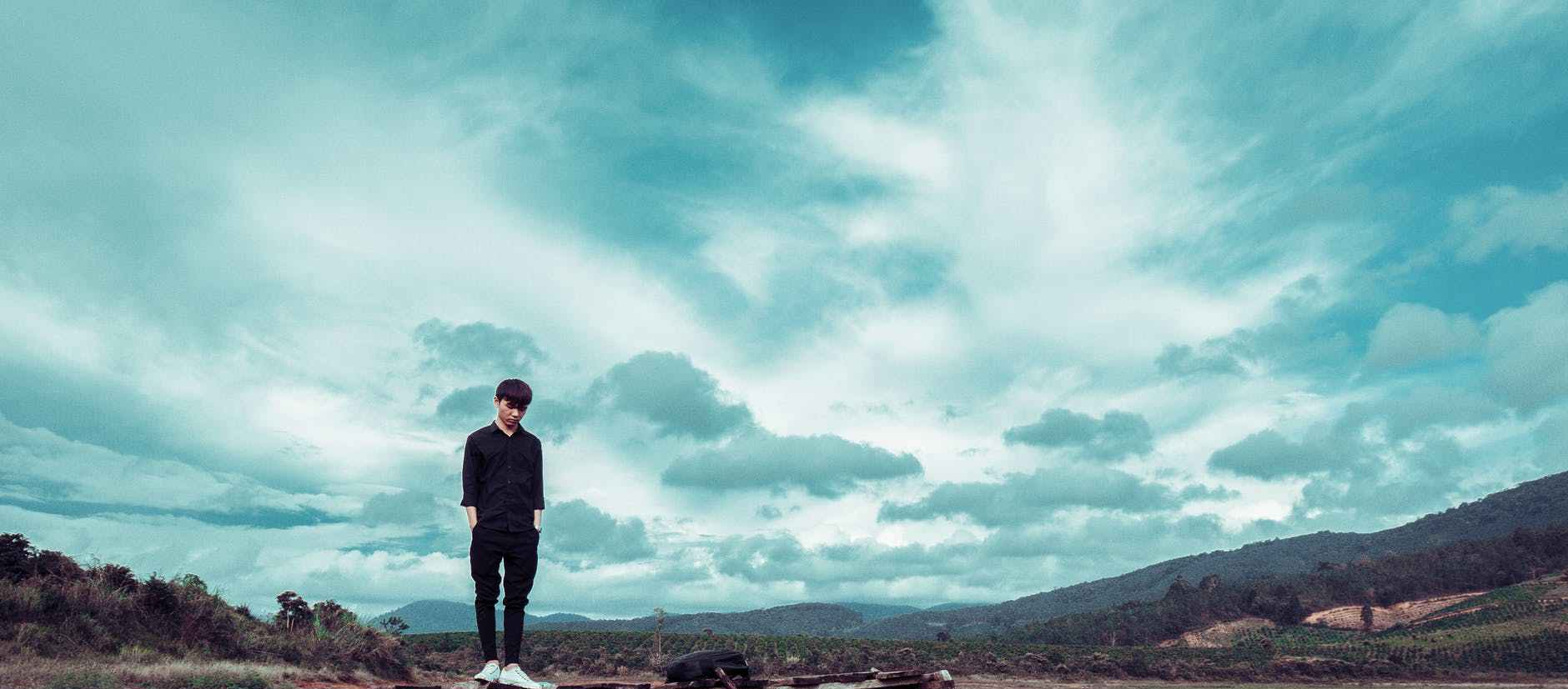 man standing on brown wooden stand with mountain at distance
