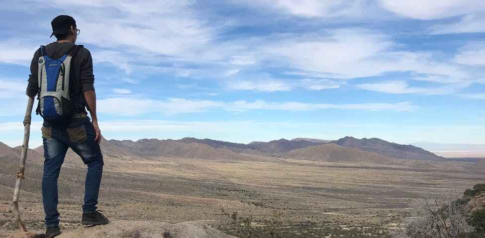 man wearing backpack standing on stone